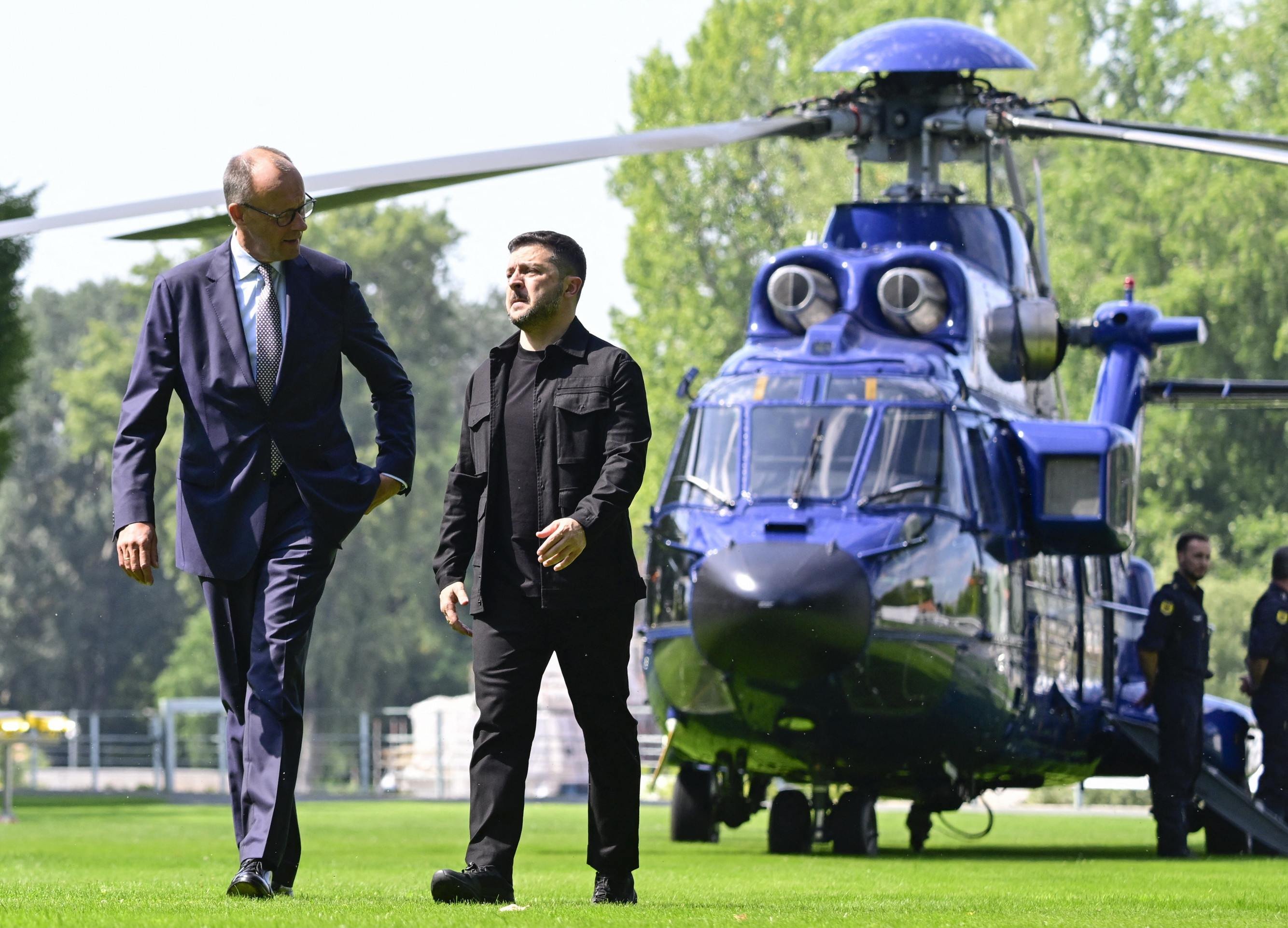 Volodymyr Zelensky (D) e o chanceler alemão, Friedrich Merz, caminham antes de cúpula por videoconferência com líderes eruropeus, em Berlim 