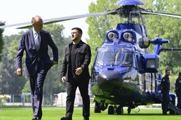 Volodymyr Zelensky (D) e o chanceler alemão, Friedrich Merz, caminham antes de cúpula por videoconferência com líderes eruropeus, em Berlim 