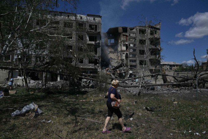 Moradora da cidade de Bilozerske, na região de Donetsk, caminha em meio a prédios destruídos pelos bombardeios russos  -  (crédito: Genya Savilov/AFP)