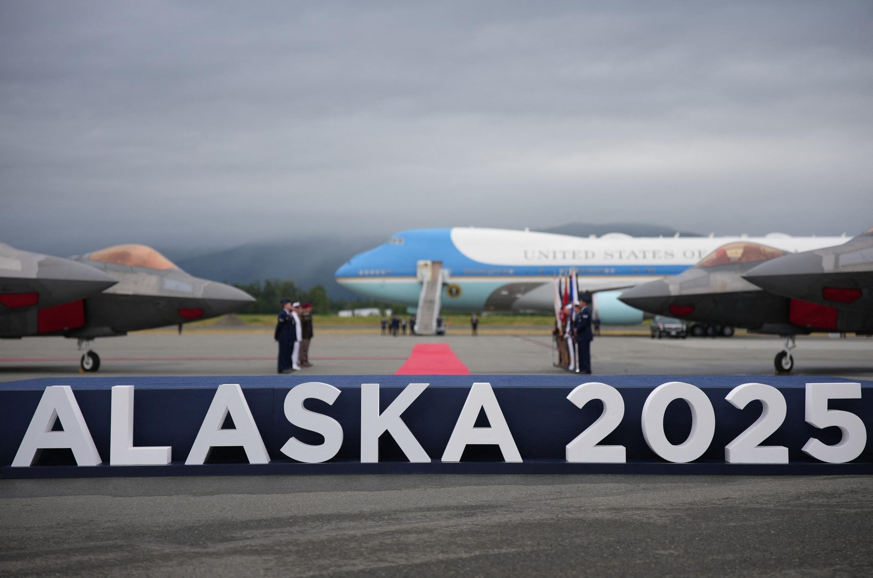  ANCHORAGE, ALASKA - AUGUST 15: An Alaska 2025 sign is seen in front of Air Force One and F-22 fighters as U.S. President Donald Trump and Russian President Vladimir Putin arrive at Joint Base Elmendorf-Richardson on August 15, 2025 in Anchorage, Alaska. The two leaders are meeting for peace talks aimed at ending the war in Ukraine.   Andrew Harnik/Getty Images/AFP (Photo by Andrew Harnik / GETTY IMAGES NORTH AMERICA / Getty Images via AFP)
      