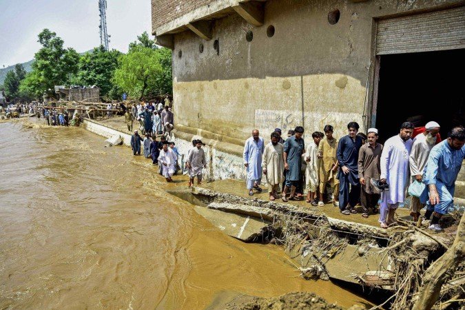 Moradores caminham ao lado de um riacho um dia após enchentes repentinas no distrito de Buner, na província montanhosa de Khyber Pakhtunkhwa, no norte do Paquistão, atingida pelas monções, em 16 de agosto de 2025       -  (crédito: HASHAM AHMED/AFP)