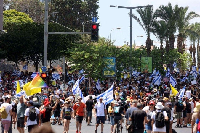 Manifestantes erguem bandeiras no domingo (17/8) durante um protesto antigovernamental exigindo um acordo para libertar israelenses detidos na Faixa de Gaza por militantes do Hamas       -  (crédito: GIL COHEN-MAGEN /AFP)