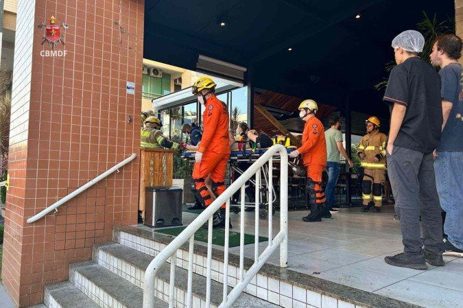 Mulher é socorrida pelos bombeiros após ser atingida por estrutura de madeira que revestia o teto de um estabelecimento comercial na 214 Norte. -  (crédito: CBMDF)