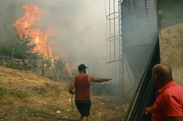 Pessoas combatem um incêndio florestal na vila de Vilarino, no município de Carballeda de Avia, noroeste da Espanha, em 17 de agosto de 2025      