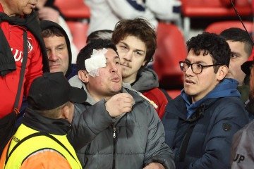 Um homem com um curativo no rosto gesticula durante a interrupção da partida de volta das oitavas de final da Copa Sul-Americana entre o Independiente da Argentina e a Universidad de Chile do Chile, no estádio Libertadores da América em Avellaneda, província de Buenos Aires, Argentina, em 20 de agosto de 2025       -  (crédito: ALEJANDRO PAGNI/AFP)
