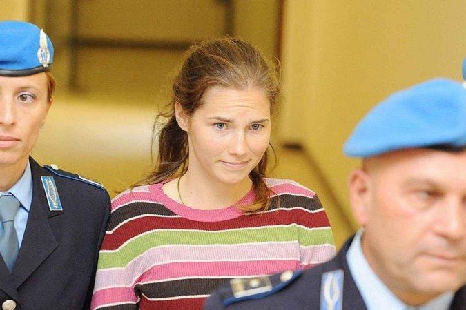 A atriz Grace Van Patten, no papel de Amanda Knox, avança por um grupo de jornalistas que tentam fotografá-la, enquanto é protegida por vários policiais -  (crédito: Disney)