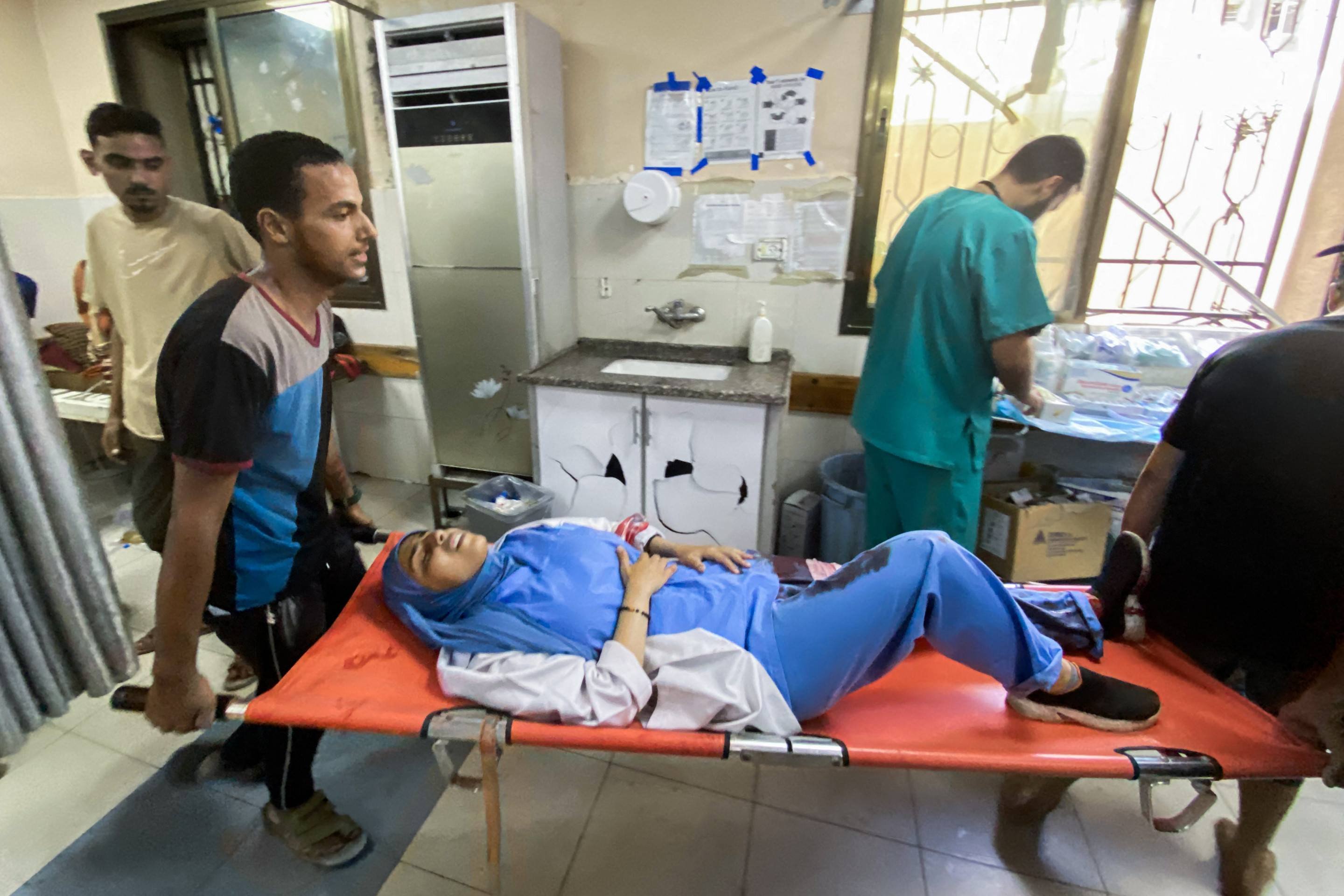 Palestinos transportam um médico ferido em ataques israelenses ao hospital Nasser em Khan Yunis, no sul da Faixa de Gaza, em 25 de agosto de 2025      