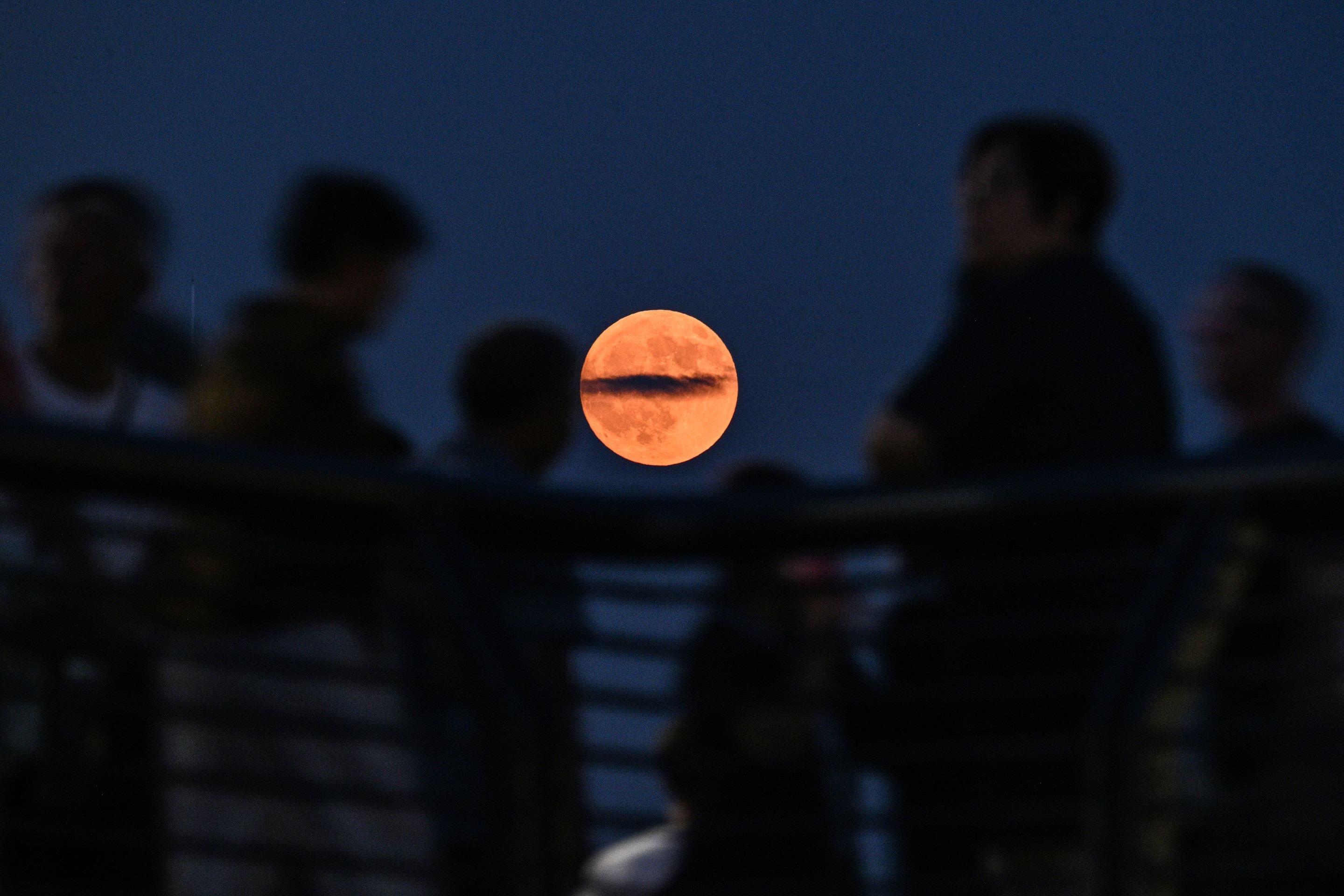 Pessoas s&atilde;o vistas no cal&ccedil;ad&atilde;o Bund ao longo do rio Huangpu enquanto a lua cheia, tamb&eacute;m conhecida como 