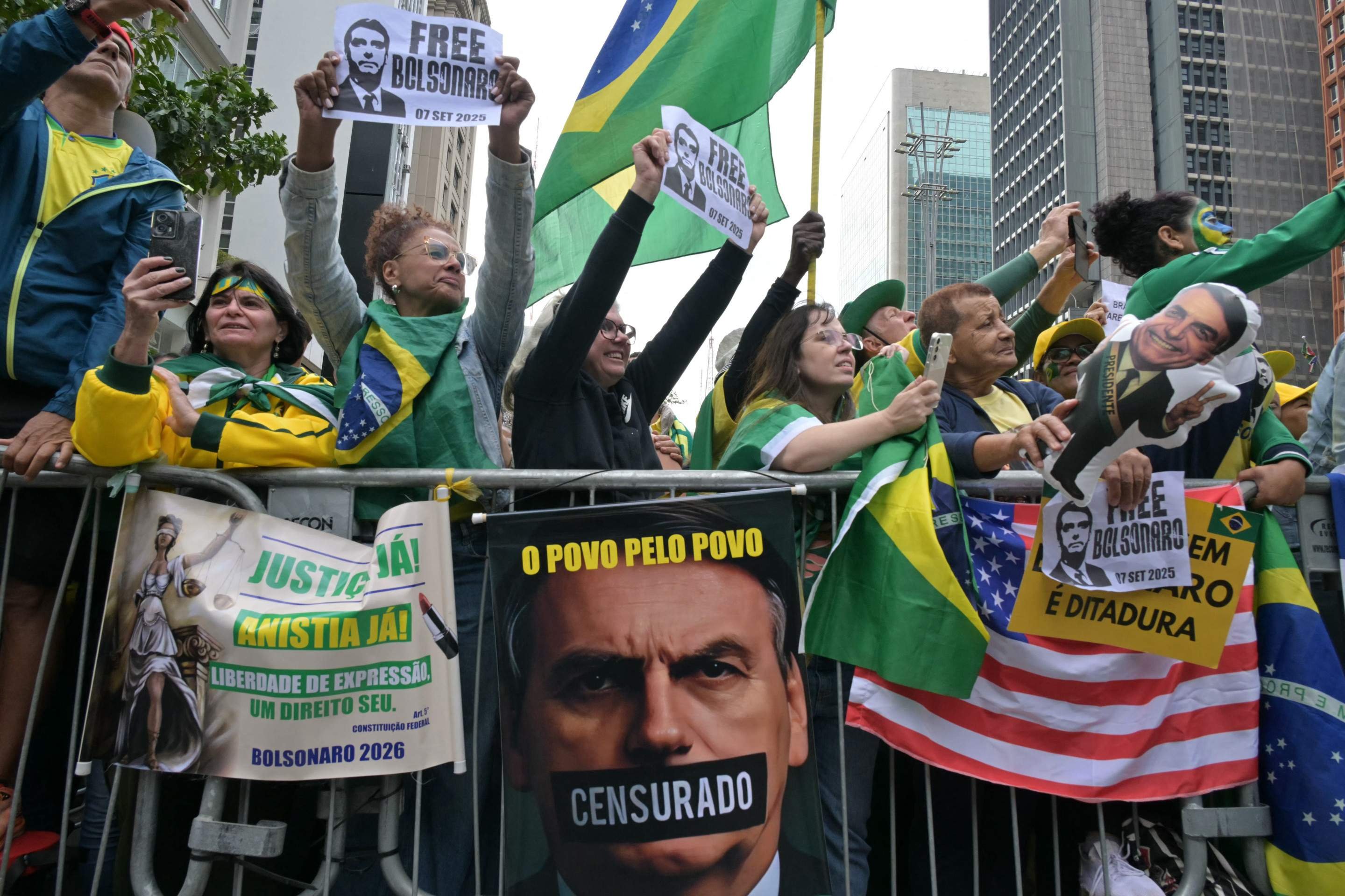 Apoiadores do ex-presidente brasileiro (2019-2022) Jair Bolsonaro, em julgamento por sua suposta participação em uma tentativa de golpe, seguram cartazes durante uma manifestação em São Paulo