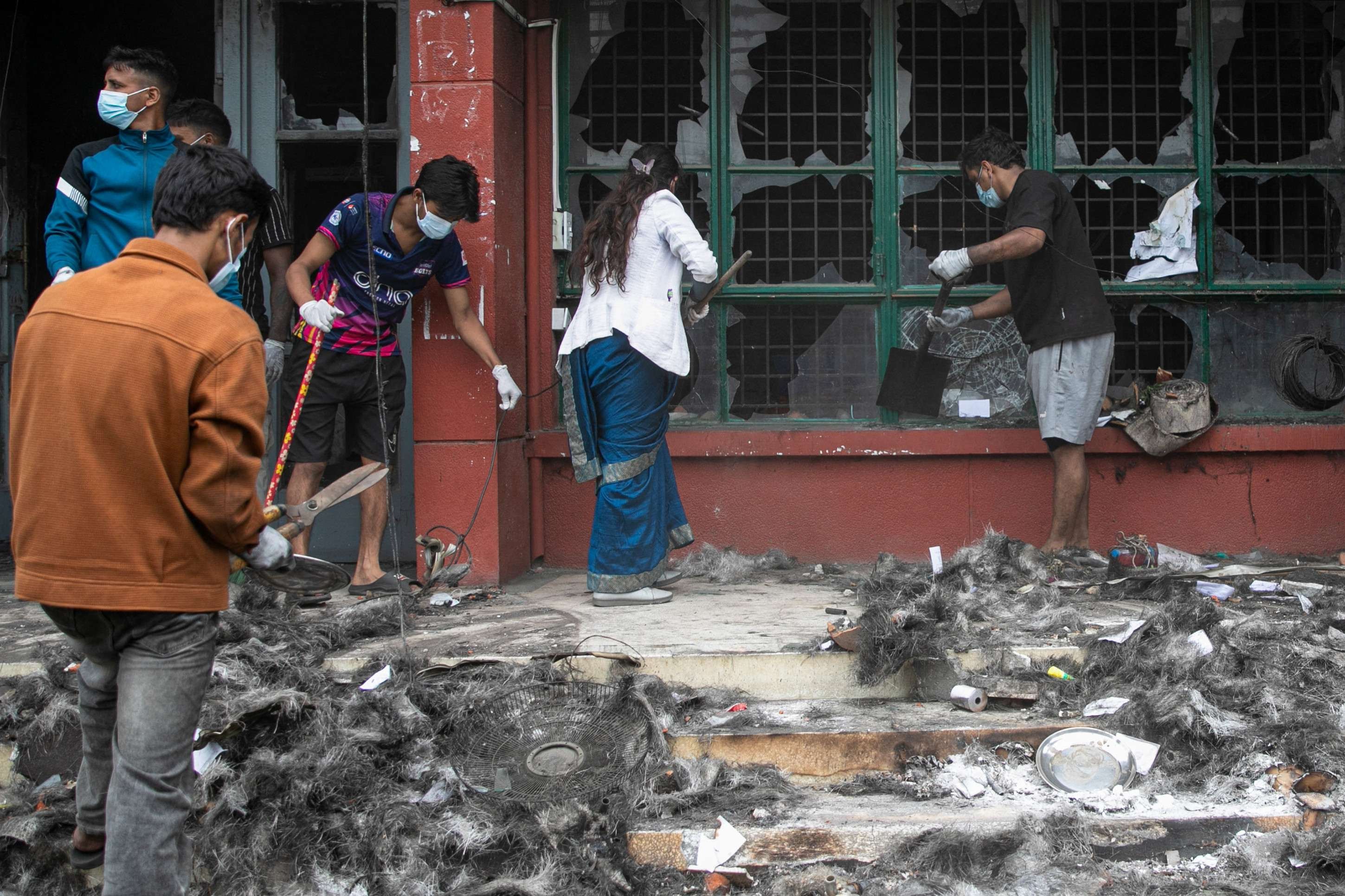 Voluntários limpam os destroços e os estragos do prédio de escritórios incendiado do Departamento de Gestão de Transportes do Nepal (DOTM) em Katmandu, em 10 de setembro de 2025. Soldados nepaleses patrulharam as ruas de Katmandu em 10 de setembro, buscando restaurar a ordem depois que manifestantes incendiaram o parlamento e forçaram o primeiro-ministro a renunciar, na pior onda de violência a atingir a nação himalaia em duas décadas.
