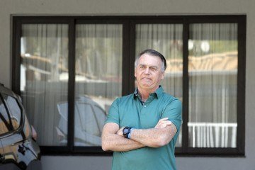  Former Brazilian President Jair Bolsonaro gestures at the garage of his residence in Brasilia on September 11, 2025. A Brazilian judge on September 10 returned the first not-guilty vote in the coup-plotting trial of former president Jair Bolsonaro, shifting all eyes on the last two of his colleagues left to vote following two guilty findings. The 70-year-old far-right ex-leader risks a prison sentence of more than 40 years if found guilty of seeking to claw back power after his defeat in 2022 elections to leftist Luiz Inacio Lula da Silva (Photo by Sergio Lima / AFP)
       -  (crédito:  AFP)