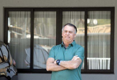  Former Brazilian President Jair Bolsonaro gestures at the garage of his residence in Brasilia on September 11, 2025. A Brazilian judge on September 10 returned the first not-guilty vote in the coup-plotting trial of former president Jair Bolsonaro, shifting all eyes on the last two of his colleagues left to vote following two guilty findings. The 70-year-old far-right ex-leader risks a prison sentence of more than 40 years if found guilty of seeking to claw back power after his defeat in 2022 elections to leftist Luiz Inacio Lula da Silva (Photo by Sergio Lima / AFP)
       -  (crédito:  AFP)