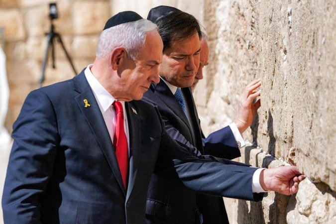 O primeiro-ministro israelense Benjamin Netanyahu, o secretário de Estado dos EUA Marco Rubio e o embaixador dos EUA em Israel Mike Huckabee visitam o Muro das Lamentações, o local de oração mais sagrado do judaísmo, na cidade velha de Jerusalém em 14 de setembro de 2025. O alto diplomata americano Marco Rubio iniciou uma visita a Israel em 14 de setembro, após expressar o apoio inabalável do governo Trump ao seu aliado na guerra com o Hamas, apesar de um ataque no Catar que atraiu muitas críticas a Israel.       -  (crédito: Nathan Howard / POOL / AFP)