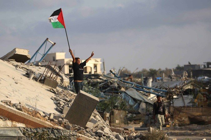 A displaced Palestinian child waves a Palestinian national flag as he stands on the rubble of a destroyed building at the Bureij camp for refugees in the central Gaza Strip on September 22, 2025. Britain, Australia, Canada and Portugal recognised the State of Palestine on September 21, a historic shift in decades of Western foreign policy that drew swift anger from Israel and a rebuke from the United States. (Photo by Eyad BABA / AFP)
- (crédito: AFP) A displaced Palestinian child waves a Palestinian national flag as he stands on the rubble of a destroyed building at the Bureij camp for refugees in the central Gaza Strip on September 22, 2025. Britain, Australia, Canada and Portugal recognised the State of Palestine on September 21, a historic shift in decades of Western foreign policy that drew swift anger from Israel and a rebuke from the United States. (Photo by Eyad BABA / AFP)
- (crédito: AFP)