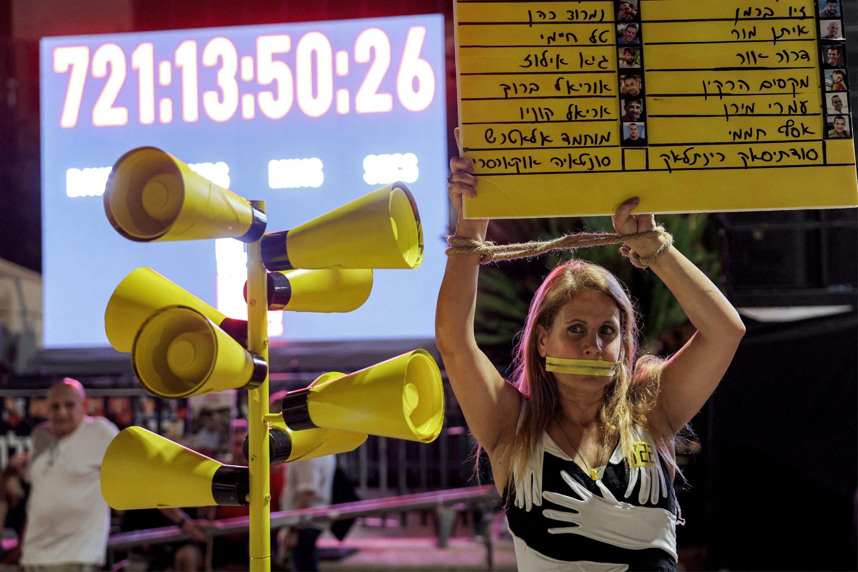  A demonstrator wearing a mouth gag holds a sign showing the names of Israeli hostages during an anti-government protest organised by the families of the Israeli hostages taken captive in the Gaza Strip since the October 2023, marking 722 days of the ongoing war between Israel and Palestinian militant movement Hamas, calling for a ceasefire and for action to secure the hostages release, outside the Tel Aviv Museum of Art (known as the 