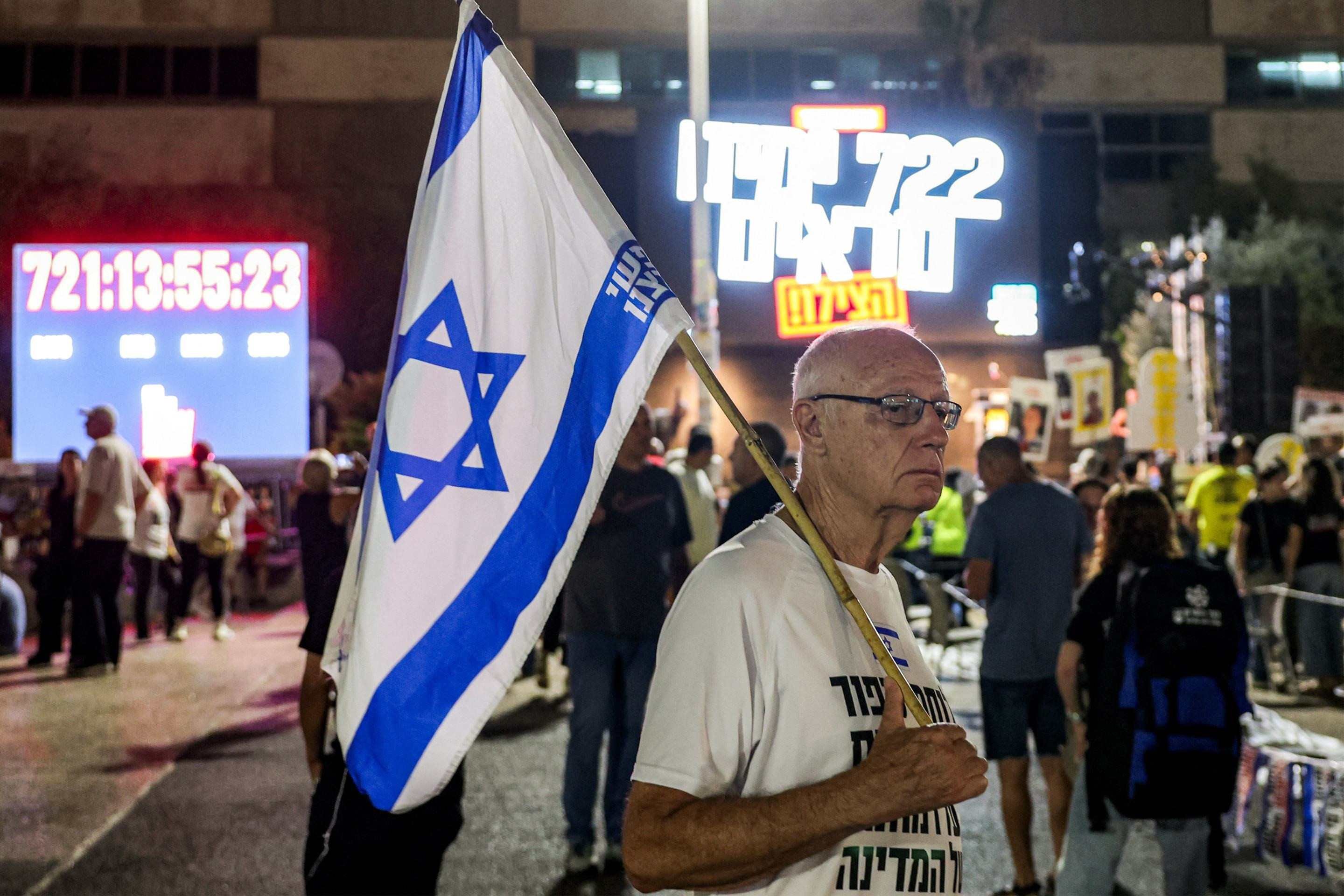  A demonstrator walks with an Israeli flag during an anti-government protest organised by the families of the Israeli hostages taken captive in the Gaza Strip since the October 2023, marking 722 days of the ongoing war between Israel and Palestinian militant movement Hamas, calling for a ceasefire and for action to secure the hostages release, outside the Tel Aviv Museum of Art (known as the 