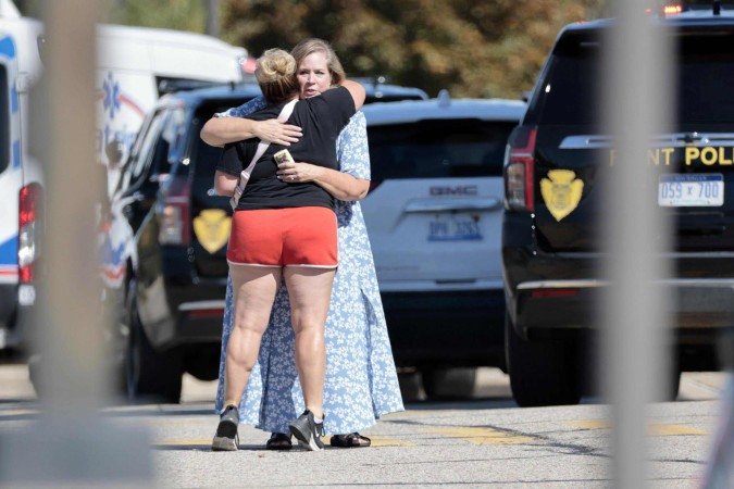  People embrace near the scene of a shooting at a church in Grand Blanc, Michigan, on September 28, 2025. One person was killed and several others injured Sunday after a shooter targeted a Mormon church in the US state of Michigan, where the building was also set on fire, authorities said.  The suspect, a 40-year-old man from a nearby town, was shot dead by law enforcement after the attack, police said, without specifying any possible motive. (Photo by Jeff Kowalsky / AFP)       