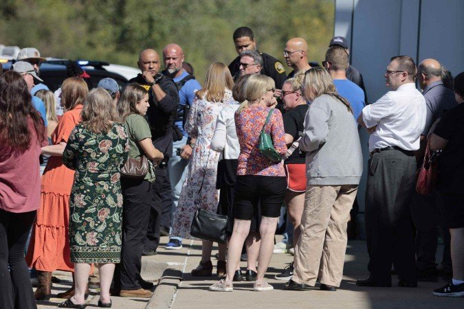  People gather near the scene of a shooting at a church in Grand Blanc, Michigan, on September 28, 2025. One person was killed and several others injured Sunday after a shooter targeted a Mormon church in the US state of Michigan, where the building was also set on fire, authorities said.  The suspect, a 40-year-old man from a nearby town, was shot dead by law enforcement after the attack, police said, without specifying any possible motive. (Photo by Jeff Kowalsky / AFP)       