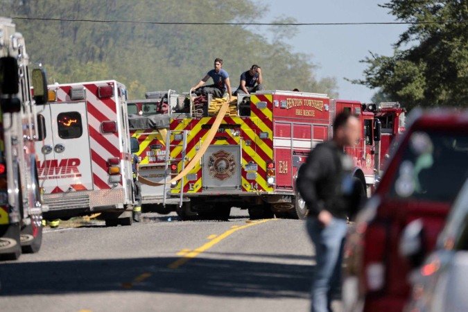  Firefighters and first responders work along a road while responding to the scene of a shooting at a church in Grand Blanc, Michigan, on September 28, 2025. One person was killed and several others injured Sunday after a shooter targeted a Mormon church in the US state of Michigan, where the building was also set on fire, authorities said.  The suspect, a 40-year-old man from a nearby town, was shot dead by law enforcement after the attack, police said, without specifying any possible motive. (Photo by JEFF KOWALSKY / AFP)       