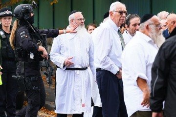Com as vestes sujas de sangue, o rabino Daniel Walker (terceiro, da esquerda para a direita) conversa com policiais: heroísmo -  (crédito: Paul Currie/AFP)