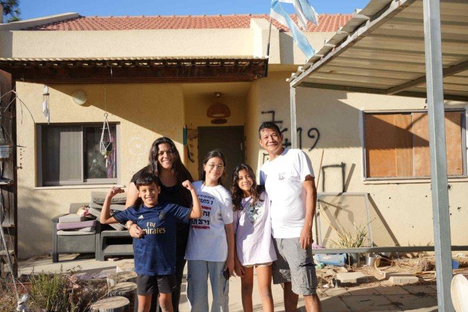 Dorin (E), Bijay (D) e os filhos diante da casa, em Nir Oz, a 2km de Gaza: tiros na parede e cômodos revirados 
