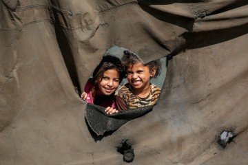Crian&ccedil;as fotografadas em buraco de barraca em acapamento para desabrigados pelos bombardeios, em Nuseirat, no centro de Gaza 
