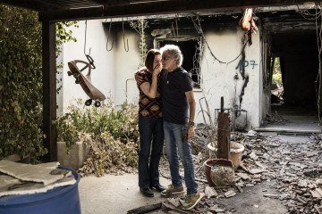 Hadar Rubin (E) se emociona ao visitar a casa da família, em Nir Oz, destruída em 7 de outubro de 2023 