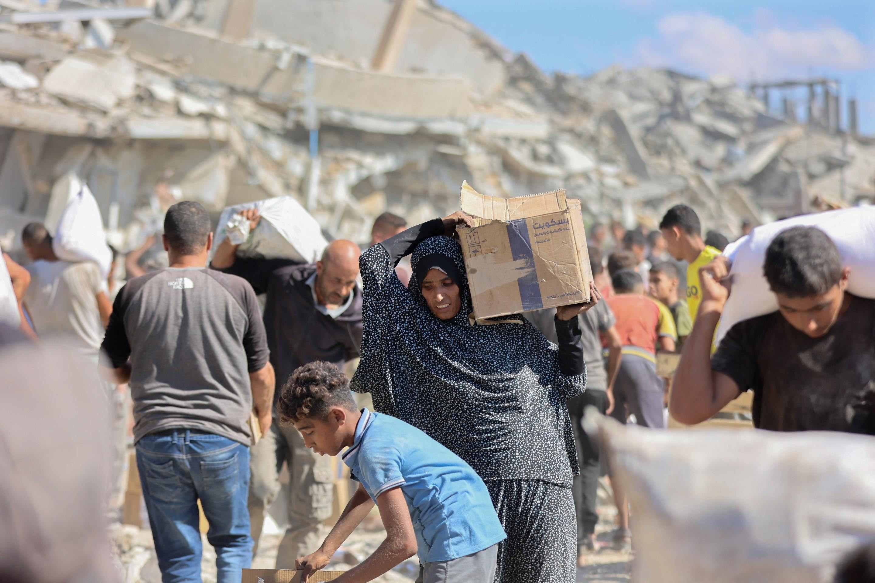 Palestinos recebem pacotes de ajuda humanitária após caminhões de ajuda humanitária entrarem pela passagem de Karem Abu Salem, em Khan Yunis, no sul da Faixa de Gaza, em 12 de outubro de 2025      