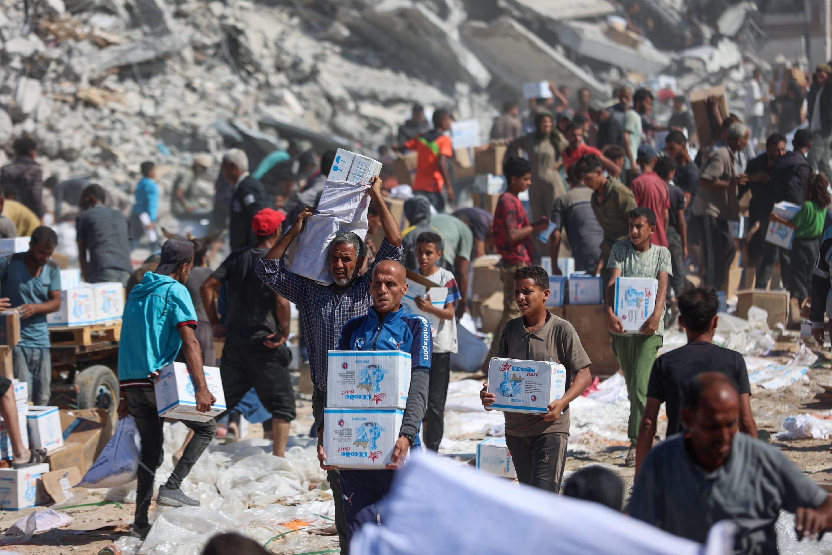 Palestinos recebem cestas básicas após a entrada de caminhões de ajuda humanitária vindos da passagem de Karem Abu Salem, em Khan Yunis, no sul da Faixa de Gaza, em 12 de outubro de 2025      