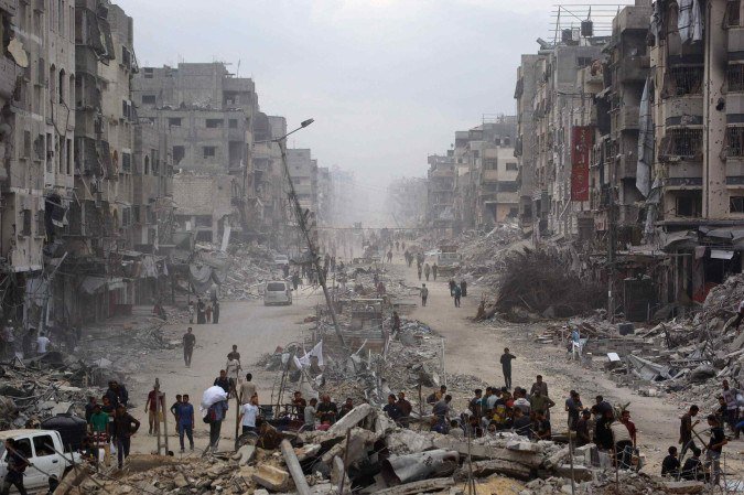 Palestinos caminham por prédios arrasados pelos bombardeios, na Cidade de Gaza 