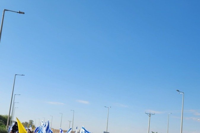 Moradores de Nir Oz aguardam reféns à beira de estrada que leva à Faixa de Gaza