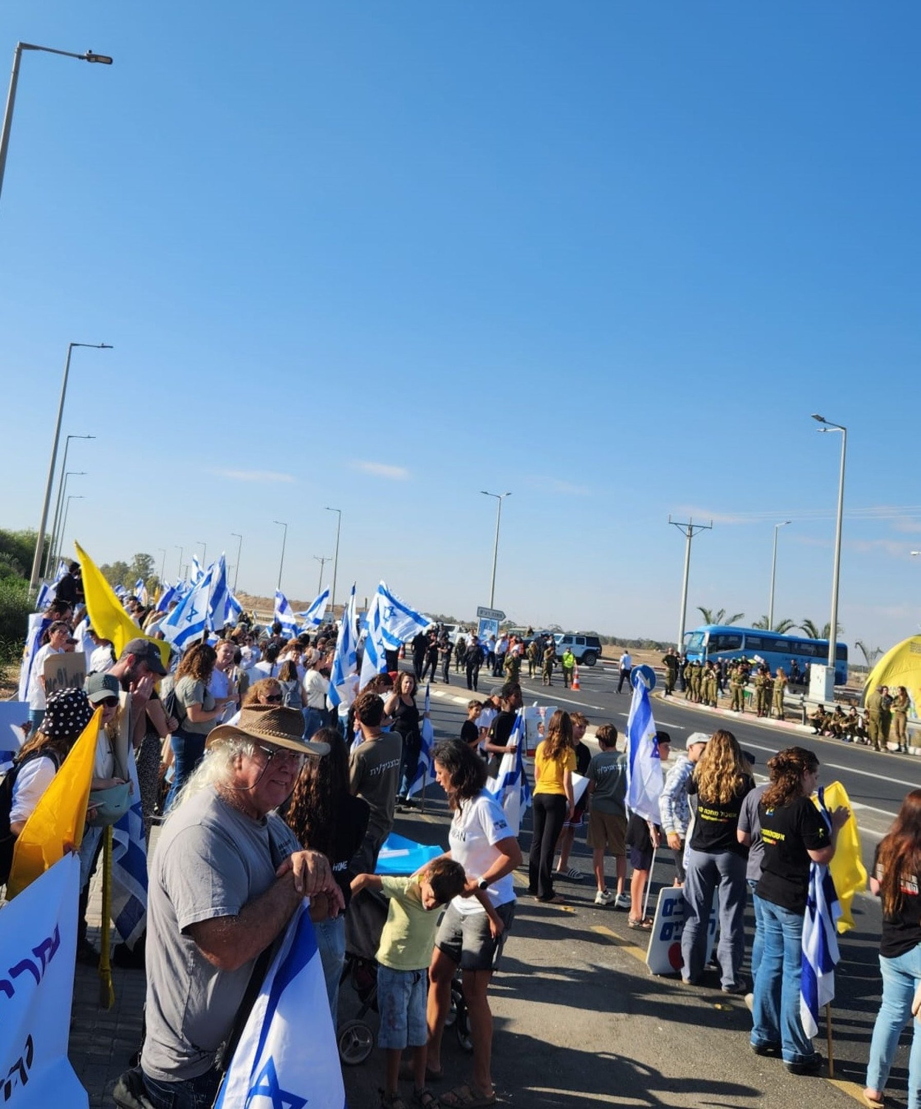 Moradores de Nir Oz aguardam passagem dos reféns, à beira de estrada que leva a Gaza