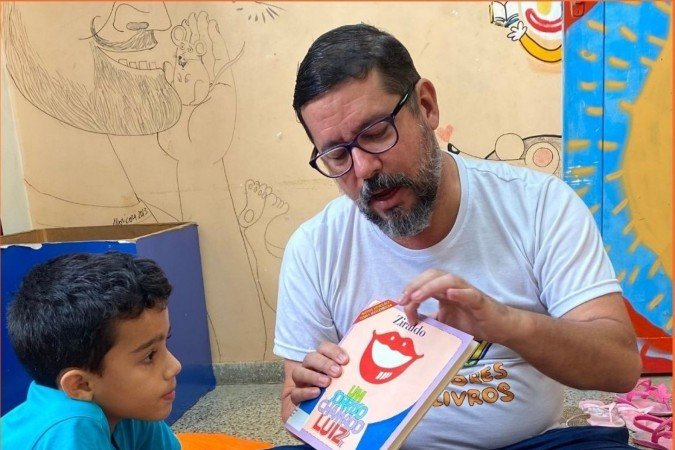 Membro do Roedores de Livros lendo para  participante do projeto 