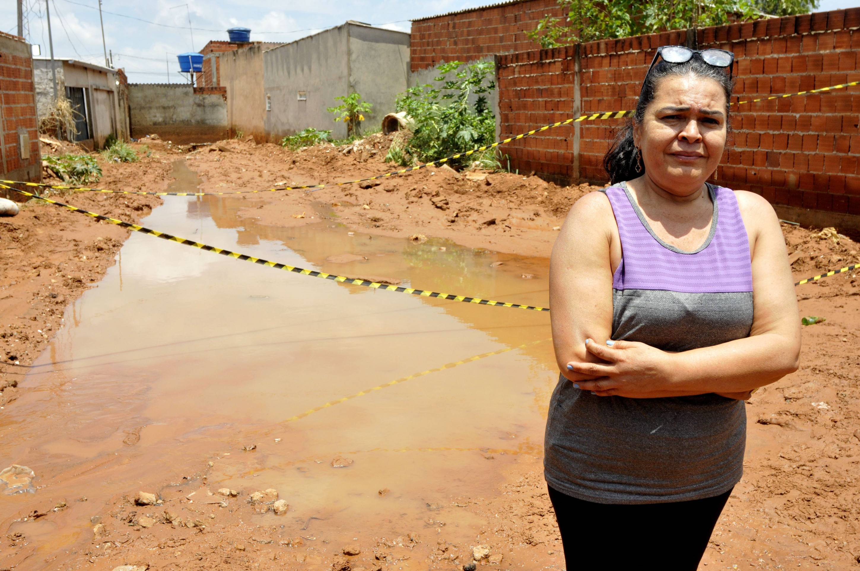 Erlândia da Silva mostra como a lama invadiu os fundos de sua casa