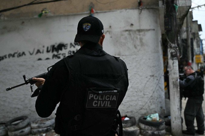 Policiais se abrigam durante a Operação Contenção na favela Vila Cruzeiro, no complexo da Penha, no Rio de Janeiro, Brasil, em 28 de outubro de 2025 -  (crédito: MAURO PIMENTEL / AFP)
