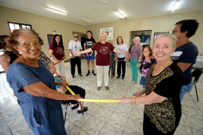Marlene Pinto, 91 anos, com os idosos da Apaz e a artista Aldanei Menegaz (no meio da roda, de braços abertos)