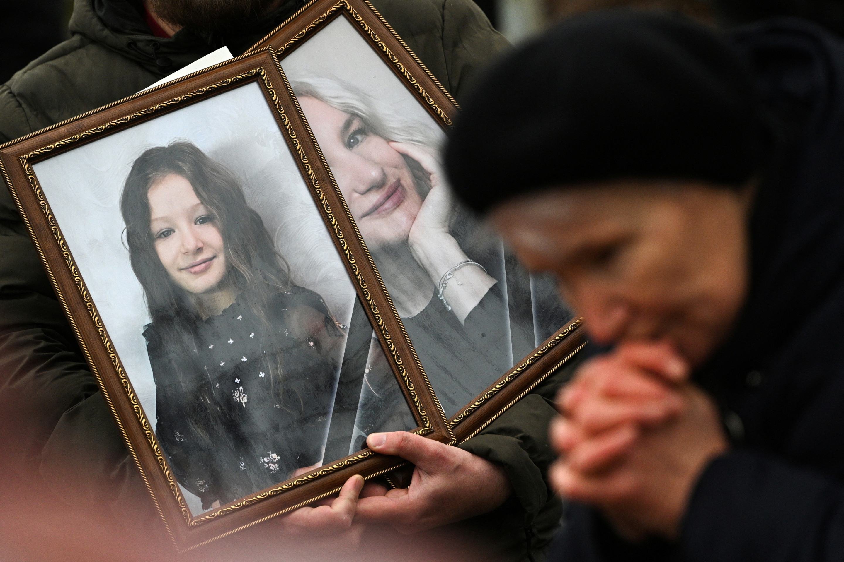 A av&oacute; de Amelia Grzesko, sete anos, morta com a m&atilde;e, Oksana, em um ataque a Ternopil,  reza diante dos t&uacute;mulos 