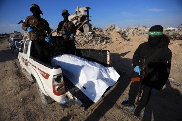 Militantes da Jihad Islâmica e do Hamas transportam restos mortais de refém israelense, em Beit Lahia (norte)