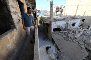 Ammar Ziadeh, de 35 anos, cofundador do jornal independente 'Enab Baladi', está em meio às ruínas de um prédio onde foi publicada a primeira edição, em Daraya, um subúrbio a sudoeste do centro da capital Damasco, em 10 de novembro de 2025.
Daraya ocupa um lugar especial na história da revolução síria. A apenas sete quilômetros (quatro milhas) da capital Damasco e à vista do extenso palácio presidencial do ex-presidente Bashar al-Assad, seus habitantes ofereceram flores aos soldados enviados para reprimir seus protestos pacíficos em março de 2011. Mas pagaram um preço muito alto por sua resistência. Pelo menos 700 pessoas foram mortas no pior massacre da guerra, em agosto de 2012, quando soldados foram de casa em casa executando qualquer pessoa que encontrassem. O regime de Assad caiu em 8 de dezembro de 2024. - (crédito: Agência France-Presse) Ammar Ziadeh, de 35 anos, cofundador do jornal independente 'Enab Baladi', está em meio às ruínas de um prédio onde foi publicada a primeira edição, em Daraya, um subúrbio a sudoeste do centro da capital Damasco, em 10 de novembro de 2025.
Daraya ocupa um lugar especial na história da revolução síria. A apenas sete quilômetros (quatro milhas) da capital Damasco e à vista do extenso palácio presidencial do ex-presidente Bashar al-Assad, seus habitantes ofereceram flores aos soldados enviados para reprimir seus protestos pacíficos em março de 2011. Mas pagaram um preço muito alto por sua resistência. Pelo menos 700 pessoas foram mortas no pior massacre da guerra, em agosto de 2012, quando soldados foram de casa em casa executando qualquer pessoa que encontrassem. O regime de Assad caiu em 8 de dezembro de 2024. - (crédito: Agência France-Presse)