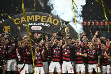  Flamengo's Uruguayan midfielder #10 Giorgian de Arrascaeta (C-L) and forward #27 Bruno Henrique (C-R) lift the Brasileirao trophy after winning the Brasileirao Serie A football match between Flamengo and Ceara at Maracana Stadium in Rio de Janeiro, Brazil, on December 3, 2025. (Photo by Mauro PIMENTEL / AFP)
       -  (crédito:  AFP)