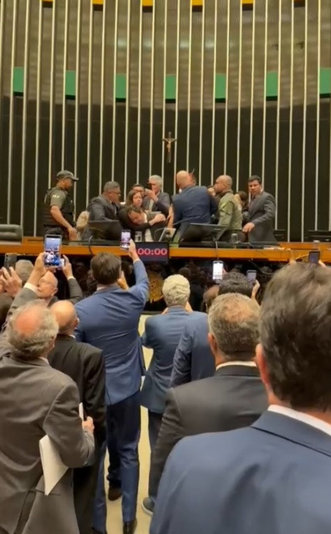  Deputado federal Glauber Braga (PSOL-RJ) é visto em meio a tumulto após ter sido retirado à força pela Polícia Legislativa da Mesa da Câmara dos Deputados, em Brasília, no final da tarde desta terça-feira, 9 de dezembro de 2025. A imprensa não conseguiu acompanhar a retirada de Glauber, que ocupou a cadeira ocupada pelo presidente da Câmara, Hugo Motta (Republicanos-PB), por se opor à votação do projeto de lei que diminui as penas de condenados pelos atos de 8 de Janeiro.