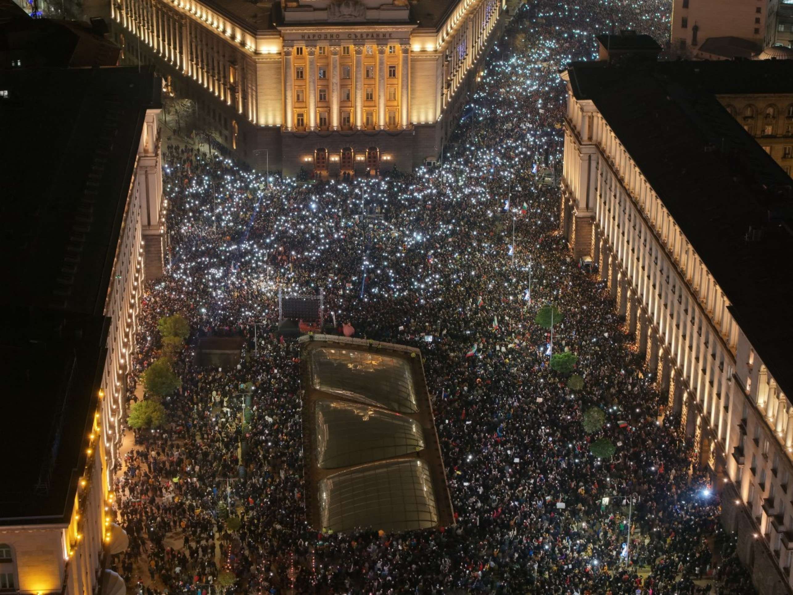 Esta fotografia aérea feita por drone mostra a multidão iluminando com seus celulares enquanto dezenas de milhares de manifestantes se reúnem no centro de Sófia para protestar contra o governo búlgaro, em Sófia, em 10 de dezembro de 2025