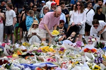  Mourners pay a floral tribute to Bondi Beach shooting victims at the Bondi Pavilion in Sydney on December 15, 2025. A father-and-son team toting long-barrelled guns shot and killed 15 people including a 10-year-old girl at Sydney's Bondi Beach on December 14, with authorities labelling it an antisemitic terrorist attack on a Jewish festival. (Photo by Saeed KHAN / AFP)
       -  (crédito:  AFP)