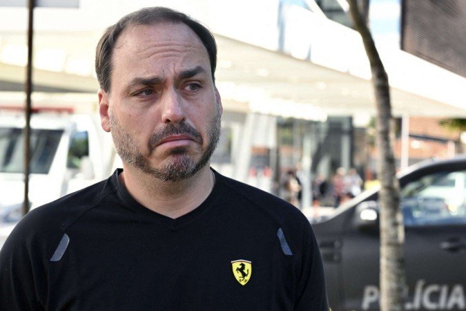 The son of former Brazil?s president (2029-2023) Jair Bolsonaro, Carlos Bolsonaro, gestures while speaking with the press outside of the DF Star Hospital where his father will undergo hernia surgery, in Brasília, on December 24, 2025. Brazil's Supreme Court on December 23, 2025 granted a request by ex-president Jair Bolsonaro -who is currently serving a 27-year sentence after being convicted of plotting a coup to remain in power following his 2022 re-election loss-.to leave prison to undergo surgery on December 25, court documents showed. (Photo by Evaristo Sa / AFP)
      Caption 
