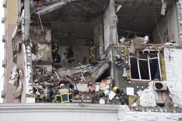 Socorristas ucranianos vasculham escombros de pr&eacute;dio atingido por m&iacute;sseis e drones russos, em Kiev, no s&aacute;bado       