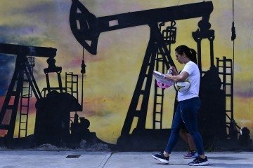 Moradora de Caracas passa por mural sobre extração de petróleo