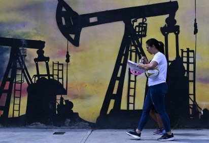 Moradora de Caracas passa por mural sobre extração de petróleo -  (crédito: Juan Barreto/AFP) -Moradora de Caracas passa por mural sobre extração de petróleo -  (crédito: Juan Barreto/AFP)