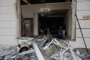 Uma mulher caminha dentro de um complexo residencial danificado após um ataque russo em Kiev, em 9 de janeiro de 2026, em meio à invasão russa da Ucrânia       -  (crédito: TETIANA DZHAFAROVA / AFP)