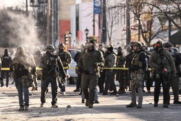  Federal agents stand near police tape as demonstators gather near the site of where state and local authorities say a man was shot by federal agents earlier in the morning in Minneapolis, Minnesota, on January 24, 2026. Minnesota Governor Tim Walz said Saturday that federal agents deployed in Minneapolis as part of a sweeping immigration crackdown had carried out 