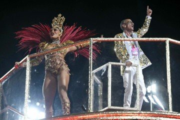 'O mestre de bateria brasileiro Mestre Ciça faz gestos ao lado da atriz Juliana Paes, durante o desfile da escola de samba Unidos do Viradouro em sua homenagem, na segunda noite do Carnaval do Rio, no Sambódromo da Marquês de Sapucaí, no Rio de Janeiro, Brasil, na madrugada de 17 de fevereiro de 2026. -  (crédito: Mauro PIMENTEL/AFP)